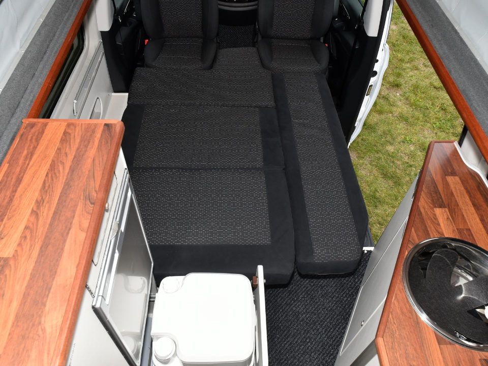 Innenansicht des Campmobils Richtung Front mit aufgebauter Liegefläche