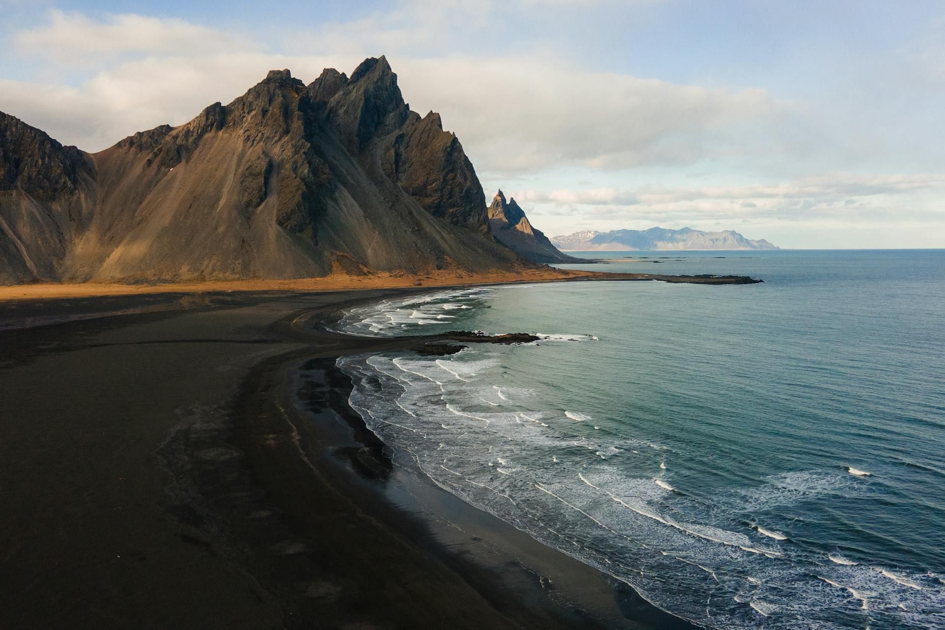 View on Iceland, rock in the background, sea on the left with dark beach.